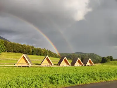 a rainbow over a group of cabins in a field at Glamp Pr Kuzuc in Cerklje na Gorenjskem