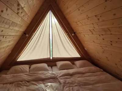 a bed in a room with a large window at Glamp Pr Kuzuc in Cerklje na Gorenjskem