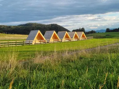 a row of tents in a field with a fence at Glamp Pr Kuzuc in Cerklje na Gorenjskem