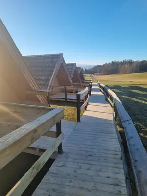 a wooden walkway leading to a house with a fence at Glamp Pr Kuzuc in Cerklje na Gorenjskem