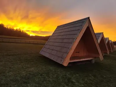 a row of huts in a field at sunset at Glamp Pr Kuzuc in Cerklje na Gorenjskem
