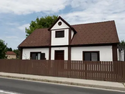 a white house with a brown roof behind a fence at Private house near Terme Čatež in Cerklje ob Krki