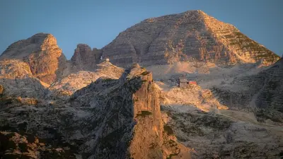 a mountain with a red house on top of it at Family Apartment Bovec in Bovec