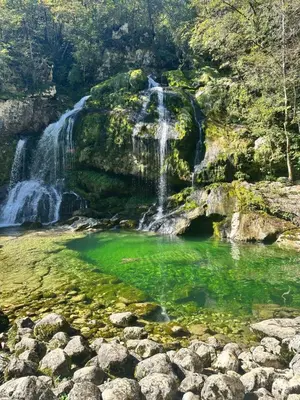 a waterfall and a pool of green water at Family Apartment Bovec in Bovec