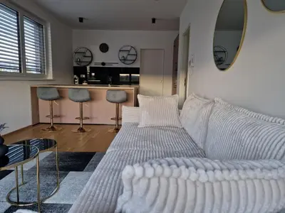 a living room with a white couch and a kitchen at Apartments Ana in Maribor
