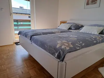 two beds in a bedroom with a large window at Apartma Gašper in Šentjur