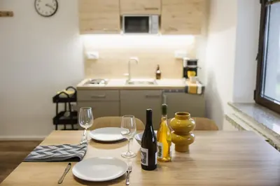 a wooden table with two plates and wine glasses at Apartma Castrum Vini in Ajdovščina