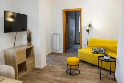 a living room with a yellow bed and a tv at Apartma Castrum Vini in Ajdovščina