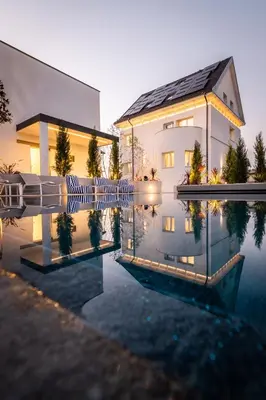 a house with a reflection in the water at Beatrice - Boutique Apartments Resort in Ljubljana