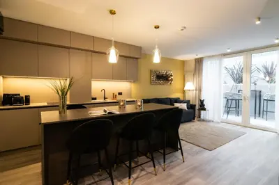 a kitchen and living room with a counter and chairs at Beatrice - Boutique Apartments Resort in Ljubljana