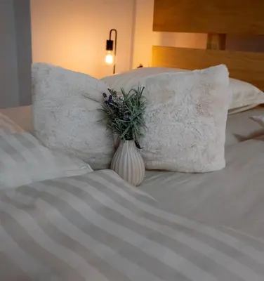 a vase with flowers sitting on a bed with pillows at Horse Whispering Ranch apartma in Ilirska Bistrica