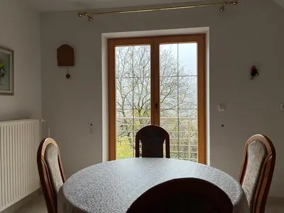 a dining room table with chairs and a large window at Pr Fajfarju in Spodnja Sorica