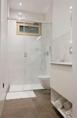a white bathroom with a shower and a toilet at Oaza Luxury Glamping Resort in Moravske Toplice
