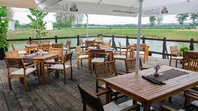 a restaurant with wooden tables and chairs on a deck at Oaza Luxury Glamping Resort in Moravske Toplice