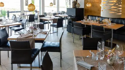 a restaurant with wooden tables and black chairs at Oaza Luxury Glamping Resort in Moravske Toplice