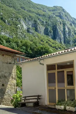 a building with a bench in front of a mountain at Farm Stay Ferjančič in Vipava