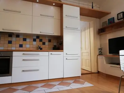 a kitchen with white cabinets and a tv at Dimora Apartments with free parking in Ljubljana