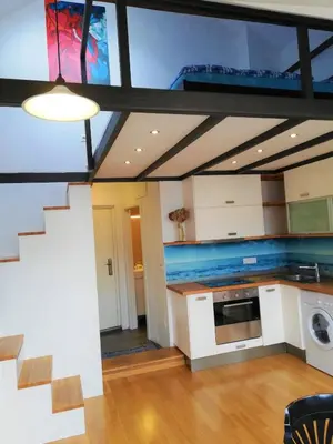 a living room with a kitchen and a staircase at Dimora Apartments with free parking in Ljubljana