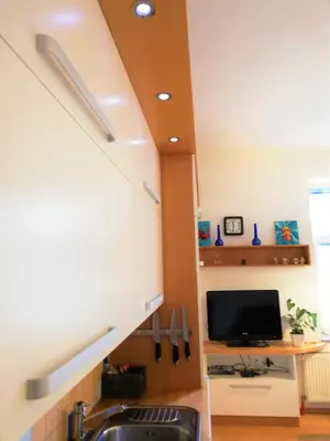 a kitchen with a sink and a tv under a stairs at Dimora Apartments with free parking in Ljubljana