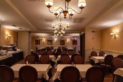 a dining room with tables and chairs and a chandelier at Hotel Ptuj in Ptuj