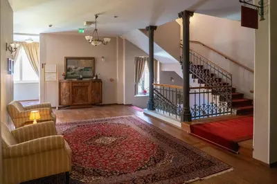 a living room with a staircase and a rug at Hotel Ptuj in Ptuj