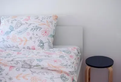 a bed with a floral pillow and a stool at Grunthouse in Prebold