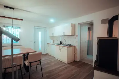 a kitchen with white cabinets and a table and chairs at SkyView Dežno in Makole