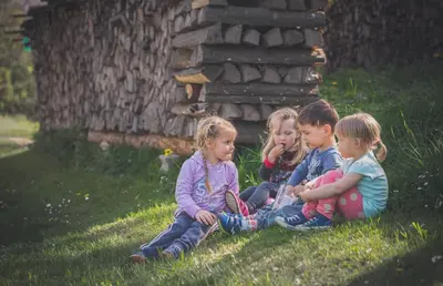 three children sitting on the grass in the yard at Farm Soržev mlin in Nova Cerkev
