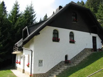 a white house with red flowers on the windows at APARTMA ARNIKA Rogla, Turistično naselje NUNE RESNIK, RESNIK 110 in Zreče
