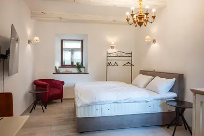 a bedroom with a bed and a red chair at Apartmaji Hiša kranjske čebele in Višnja Gora
