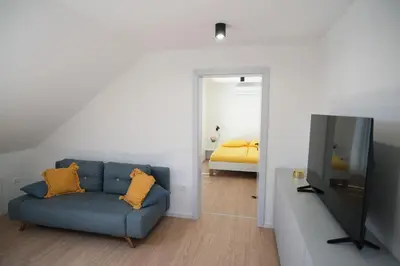 a living room with a blue couch and a television at Apartma Eva in Krško