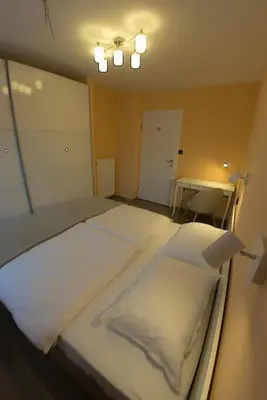 a bedroom with a bed with white sheets and a table at Apartment Golovec in Ljubljana