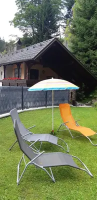 two lawn chairs and an umbrella in the grass at Apartment Tarman in Jesenice