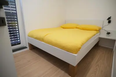 a bed with yellow sheets and pillows in a bedroom at Apartma Ana in Krško