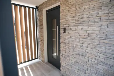 a hallway with a stone wall and a black door at Apartma Ana in Krško
