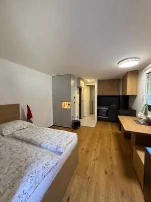 a bedroom with a large bed and a kitchen at Mounti Alpine Studio in Kranjska Gora