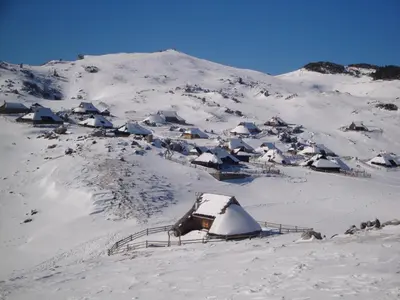 a snow covered mountain with a group of houses at Chalet Tisa Velika Planina in Stahovica