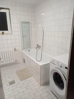 a bathroom with a tub and a washing machine at KaTi Hiša