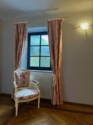 a chair in a room with a window at Baroque Alpine Retreat at the Historic Premetovc in Škofja Loka