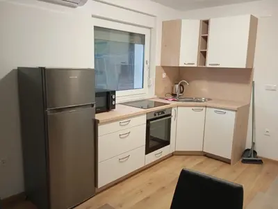 a kitchen with a stainless steel refrigerator and white cabinets at Apartmaji Divji vrt in Lendava