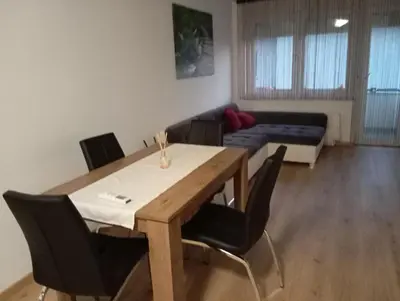 a dining room with a table and chairs and a couch at Apartmaji Divji vrt in Lendava