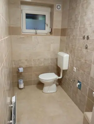 a bathroom with a toilet and a television in it at Apartmaji Divji vrt in Lendava