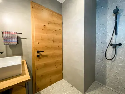 a bathroom with a shower and a wooden door at KOČA ODMEV Obolno in Ivančna Gorica