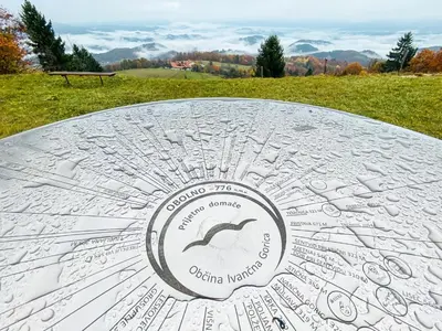 a metal table with a sign on top of a field at KOČA ODMEV Obolno in Ivančna Gorica