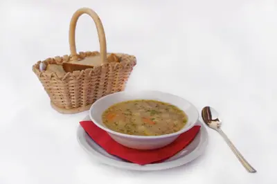 a bowl of soup on a plate next to a basket at Ekološka turistična kmetija pri Lovrču in Tolmin