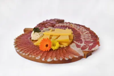 a plate of food with different types of cheese and meats at Ekološka turistična kmetija pri Lovrču in Tolmin