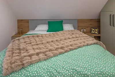 a bed with a brown blanket and a green pillow at Počitniška hiša Gorski Šepet Bled in Bled