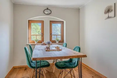 a dining room with a wooden table and green chairs at Vila Trate with Shared Pool and Garden in Ljutomer
