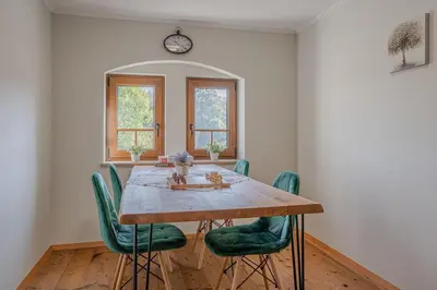 a dining room with a wooden table and green chairs at Vila Trate with Shared Pool and Garden in Ljutomer