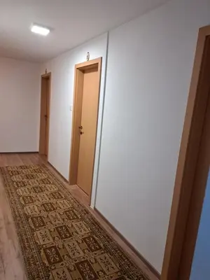 a hallway with white walls and a door and a rug at Gostišče Jelka in Pohorje